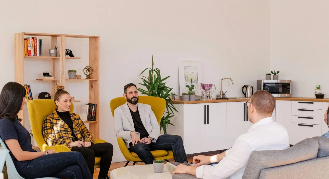 Five people in armchairs talking in a relaxed lounge setting