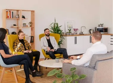 Five people in armchairs talking in a relaxed lounge setting